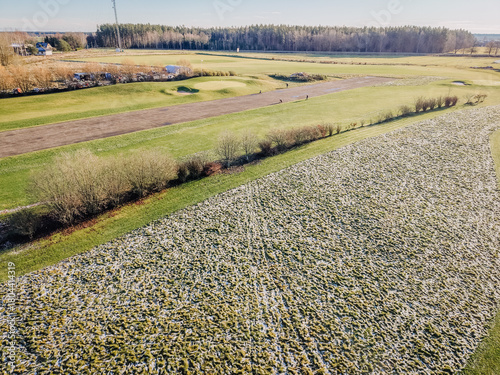 Slika na platnu Aerial view of a lush green landscape with patches of snow, showcasing a serene