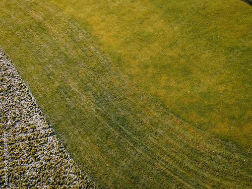 Tapeta Aerial view of a vibrant green lawn transitioning to a textured patch of dry gra