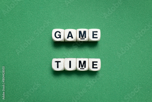 Wooden dice spell 'GAME TIME' shot isolated over a green baize cloth.