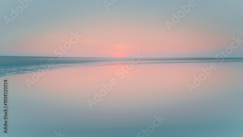 Photography Calm water reflects a fading sunset on a wide, flat beach, with a low horizon line