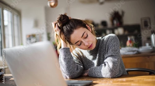 Tired Woman Resting at Desk While Working from Home, Exhausted Student or Worker Leaning on Hand in Front of Laptop, Fatigue and Burnout During Remote Work in a Home Office