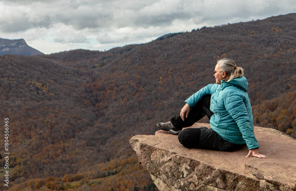 Naklejka premium Serenity found on a rocky ledge with breathtaking mountain views and autumn colors in the distance