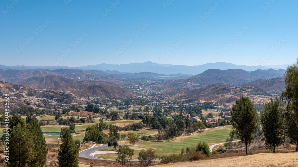 Obraz premium Scenic View of Rolling Hills and Golf Course Surrounded by Lush Greenery Under Clear Blue Sky in a Serene Landscape