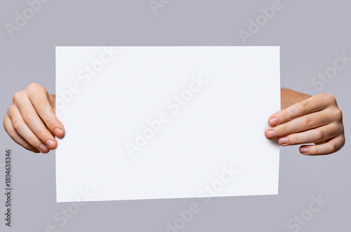 Copy space for your text. Man's hands holding empty board isolated on gray background. Closeup. Close up of a woman hand holding empty blank white board, your text here concept