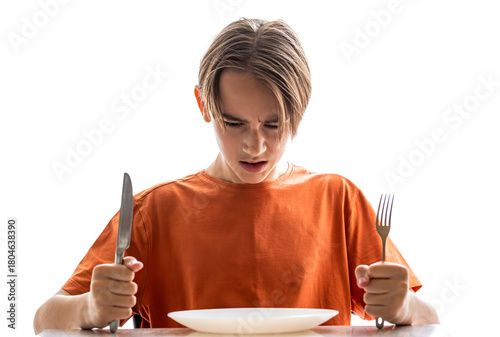 Obraz na płótnie Upset little boy waiting for dinner while holding a fork, spoon