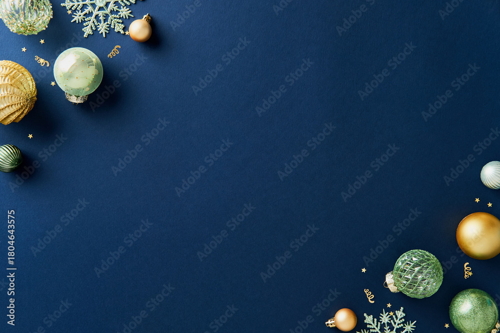 Obraz premium Corner Christmas composition with shiny gold and green Xmas decorations on navy blue background. Flat lay, top view, copy space.