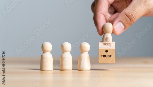 Four wooden figurines on wood surface, one lifted onto “TRUST” block with keyhole symbol.