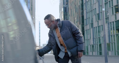Man Checking Watch and Charging Electric Vehicle