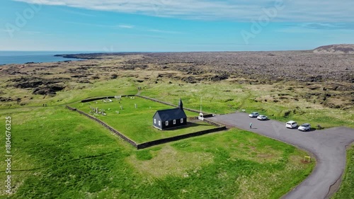Aerial landscape of Búðakirkja Black Church, Iceland. Minimalist architecture in remote green fields.
