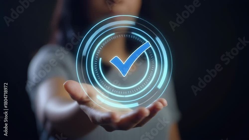 Person holding a glowing blue checkmark symbol within a futuristic circular interface on a dark background Keywords: checkmark, symbol, approval, success