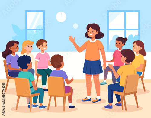 A young female teacher stands and speaks to a diverse group of children sitting in chairs in a circle in a classroom.