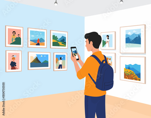 A young man with a backpack photographs artwork displayed on a blue wall inside an art gallery using his smartphone.