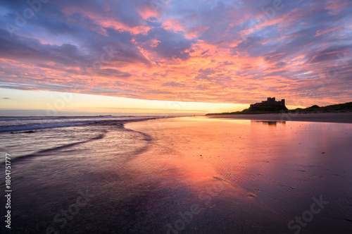 Dramatic sunrise above beach at Bamburgh Castle on The Northumberland Coast, UK.