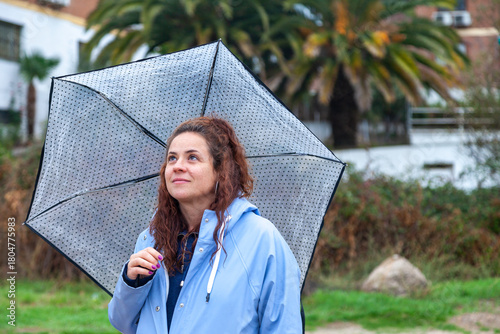 Real Young Woman in Blue Raincoat with Umbrella on a Rainy Day.