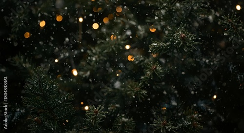 A close up view of a christmas tree with lights and snow falling in the dark night time