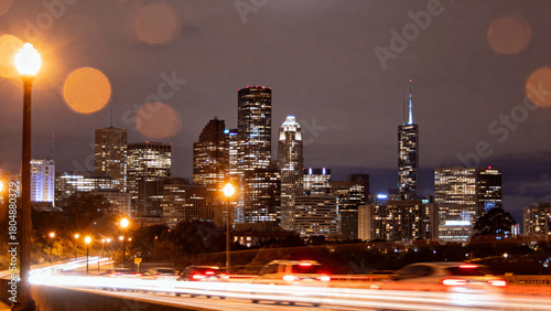 Nighttime city skyline with illuminated skyscrapers and traffic light trails