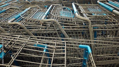 A photo of numerous metal grocery trolley shopping carts close-up with blue plastic handles, stacked or pushed together. retail economy background.