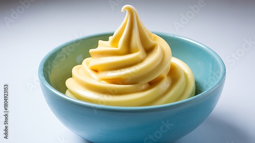 Creamy yellow soft serve ice cream swirl in blue bowl dessert