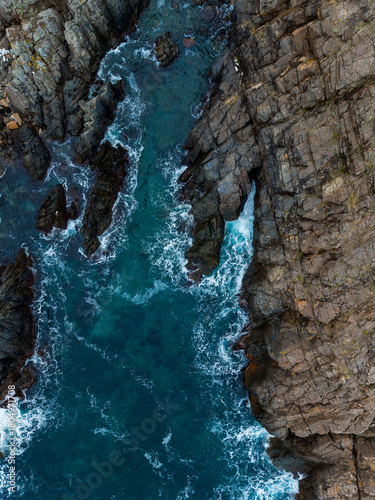 Waves crashing against rugged cliffs at dusk near the coastline in a serene coastal landscape
