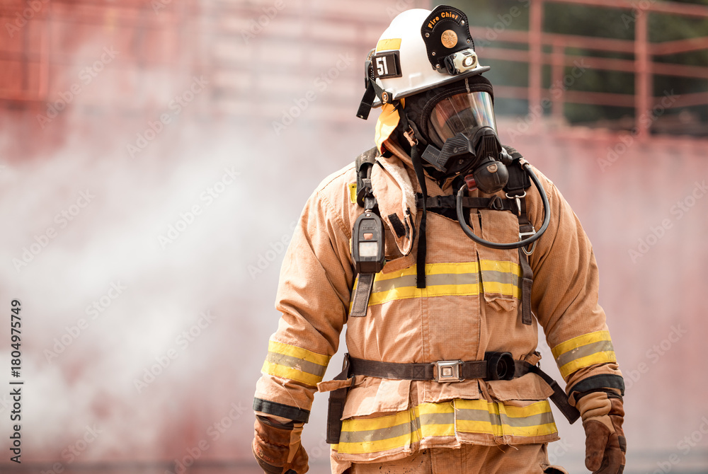 Naklejka premium A firefighter in full protective gear takes a break after exiting a smoke-filled building