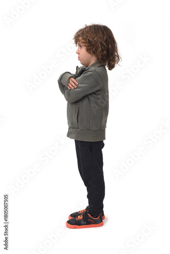 side view of a  boy dressed in sportswear arms crossed on a white background