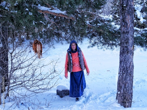 A young woman is walking in the snow with a horse behind her. Georgia - February 2025.