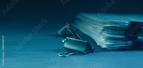 Pile of documents and binder clips on dark blue background.