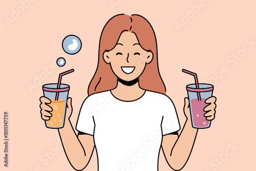 A happy person holds two different colorful drinks with straws, contemplating which one to choose.