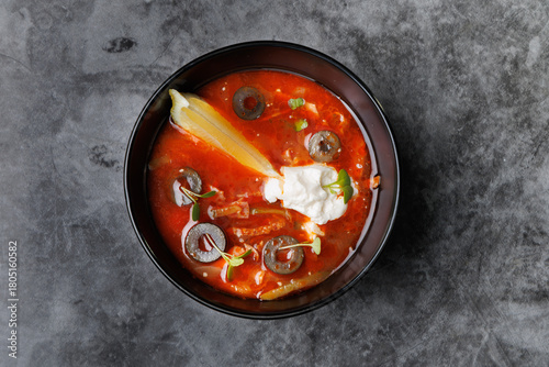 Red Tomato Soup In Black Bowl With Olive Slices, Cream