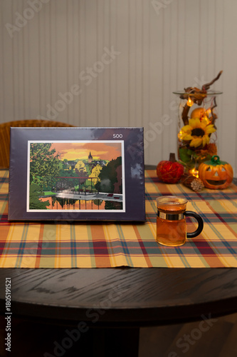A 500 piece jigsaw puzzle lies on the table in an autumnally decorated apartment. It shows an illustration of the town of Brilon in the Sauerland region. A hot cup of tea symbolizes a cozy pastime.