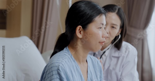 Hospital concept of 4k Resolution. Asian doctor using stethoscope to check patient in hospital room.