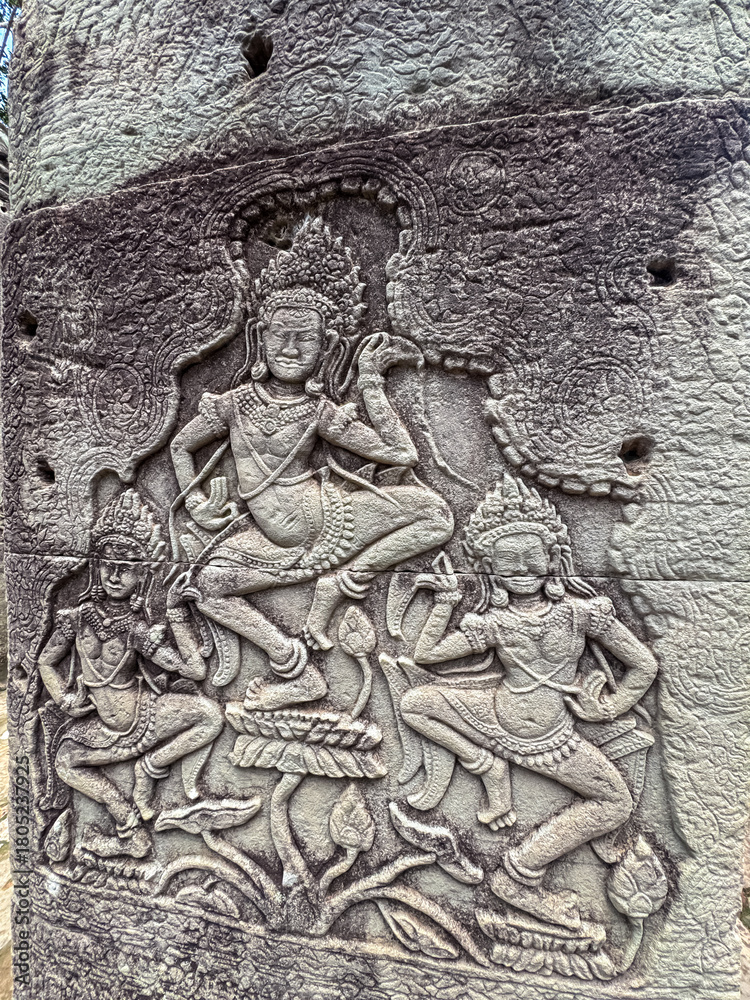 Naklejka premium An intricate and well-preserved bas-relief carving shows celestial Apsara dancers in motion on a weathered stone wall, showcasing ancient Khmer artistry at a temple in Siem Reap, Cambodia.