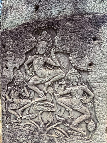 An intricate and well-preserved bas-relief carving shows celestial Apsara dancers in motion on a weathered stone wall, showcasing ancient Khmer artistry at a temple in Siem Reap, Cambodia.