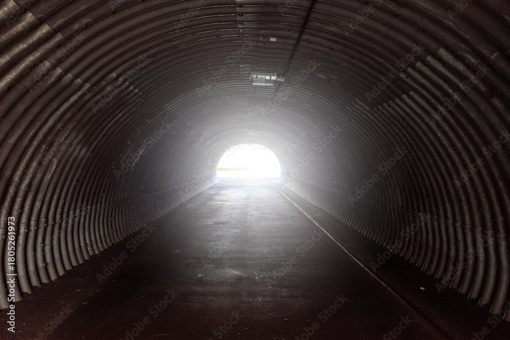 Fototapeta premium dark, corrugated metal tunnel leading to a bright light