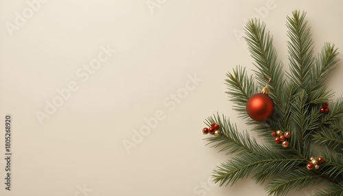 a festive christmas arrangement featuring a vibrant red ornament nestled amongst lush evergreen branches on a neutral backdrop
