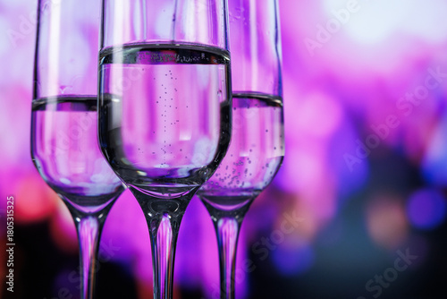 stylish stemmed glasses highlight effervescent drinks amidst colorful neon lighting for nightlife promotion