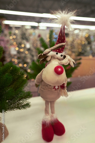 A selection of Christmas interior decorations. A stuffed reindeer with a red nose at the Christmas market.