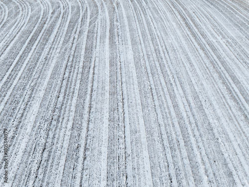 Aerial drone view of a plowed agricultural field covered in fresh white snow featuring rhythmic linear patterns and winter texture.