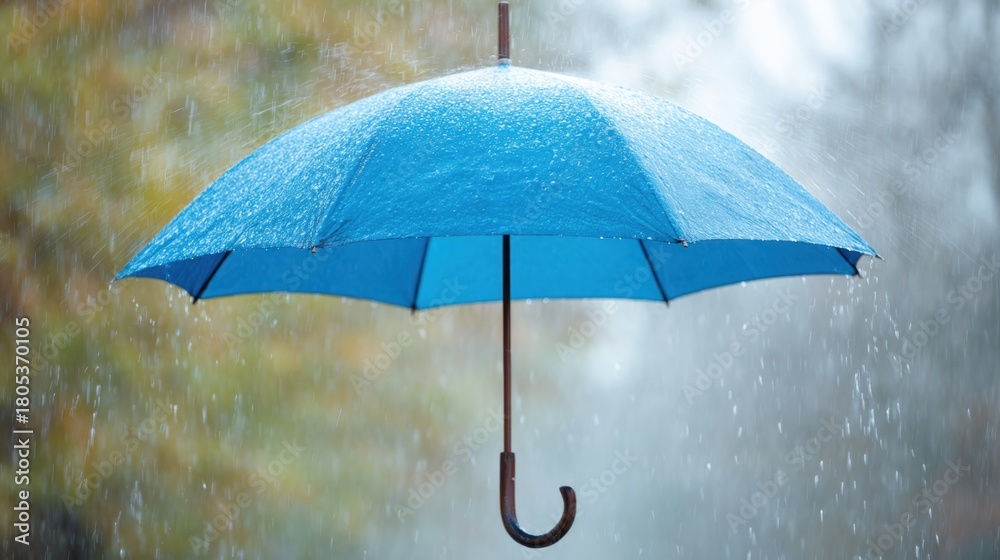 Naklejka premium A blue umbrella is being used to shield someone from the rain. The umbrella is open and the rain is falling, creating a wet and gloomy atmosphere