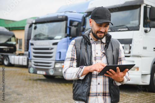 Schilderij op canvas Truck driver managing logistics using tablet computer at fleet terminal