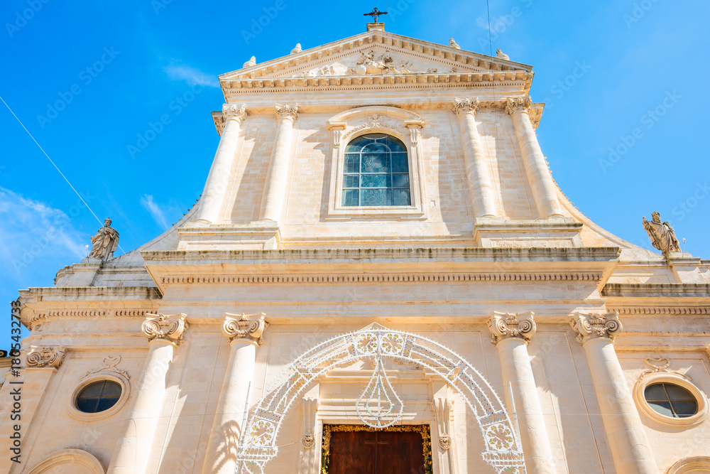Obraz premium Majestic Baroque-style church facade glowing under the bright blue sky in Locorotondo town, Apulia, Italy