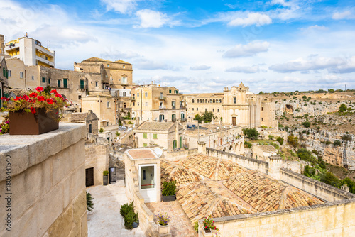 Scenic view of old town rooftops, churches, and canyon landscape under blue skies in Matera town, Apulia, Italy