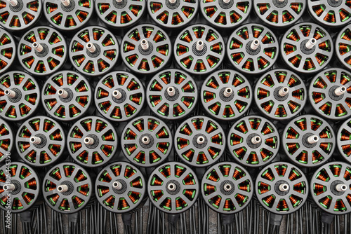 numerous brushless FPV drone motors closely packed. internal copper windings are clearly visible through the open gray stator bells