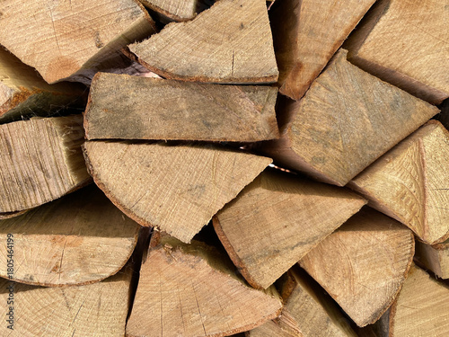 A close-up, full-frame texture of neatly stacked, split firewood. The seasoned logs form a dense, rustic background and geometric pattern perfect for themes of winter, warmth, and natural energy