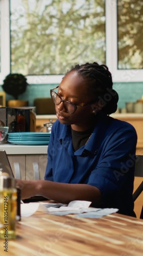 Vertical Video African American couple managing finances sitting at the kitchen table. Checking paperwork and bills or invoices, using laptop for easy money management, financial planning at home