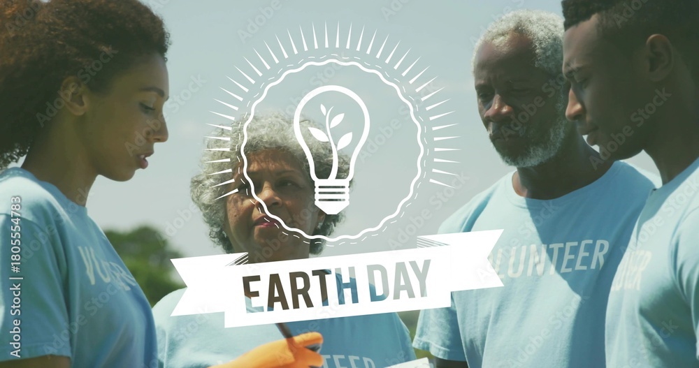 Fototapeta premium Uniting team checking list in park in blue VOLUNTEER tees with orange gloves near EARTH-DAY banner