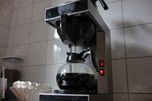 Intimate view of coffee maker brewing mechanism with fresh coffee dripping into glass carafe