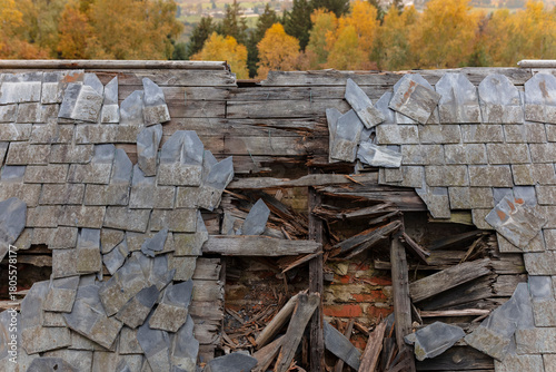 Heavily damaged roof section showing broken slate tiles and structural collapse