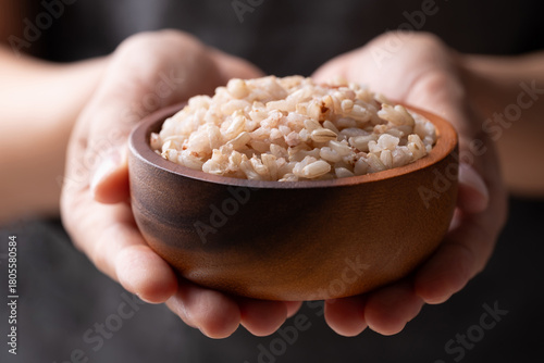 Cooked Thai brown rice in a wooden bowl holding by hand, Healthy eating