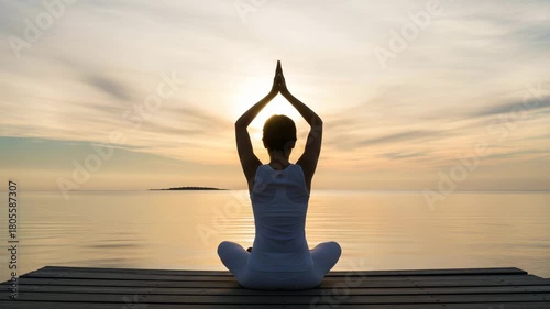 Woman meditating in lotus pose on wooden pier at sunset over calm water yoga meditation